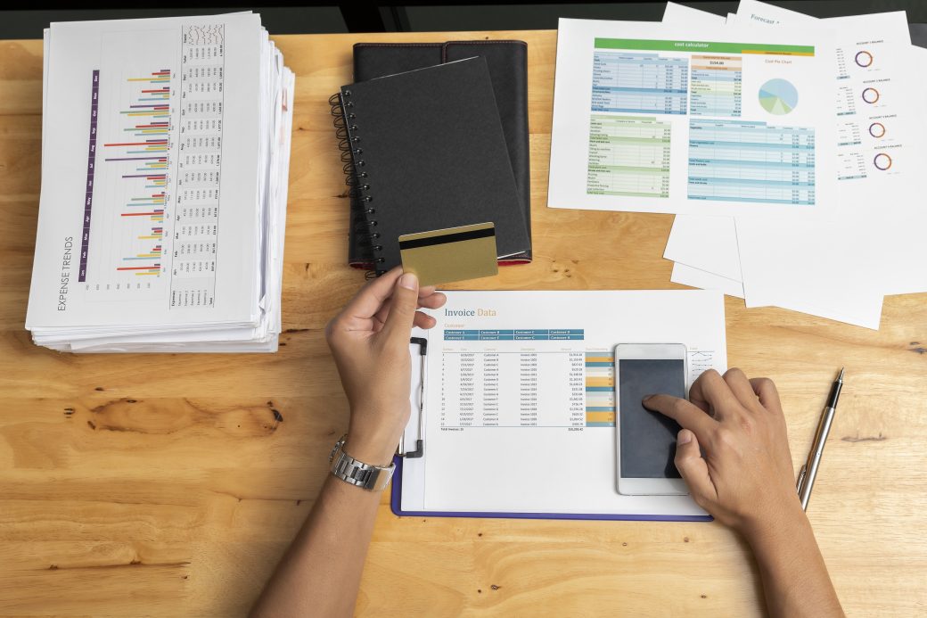 A person using a smartphone and credit card at a desk — the kind of everyday AI-driven decision an audit examines