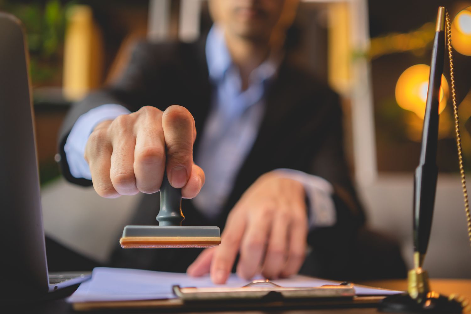An executive stamping and signing off on documents at an office desk